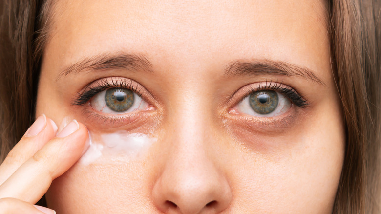 Applying cream to dark eye circles