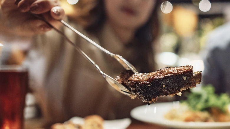 Blurred woman with meat in tongs