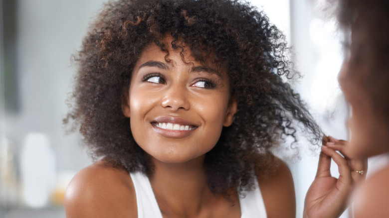 woman looking at hair in the mirror