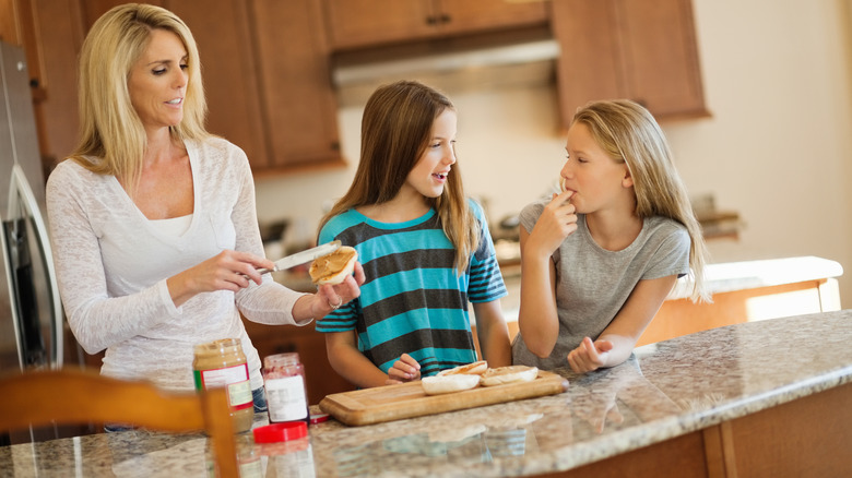 mother adding peanut butter to bread for kids