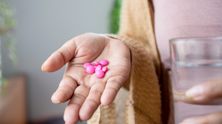 woman's hand holding ibuprofen tablets