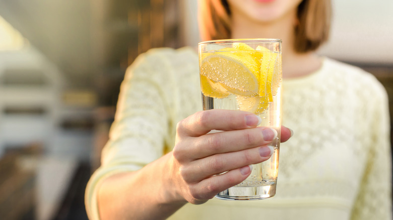 woman holding lemon water glass