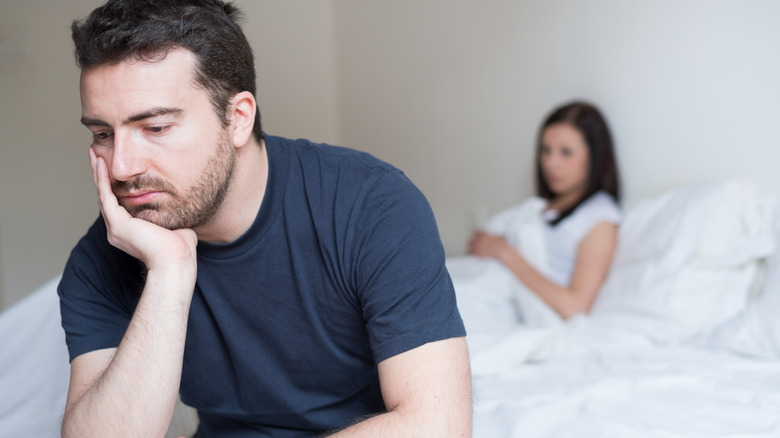 man looking stressed sitting on bed