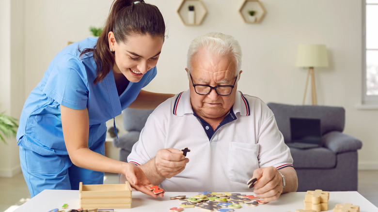 Health worker helping older man with a puzzle