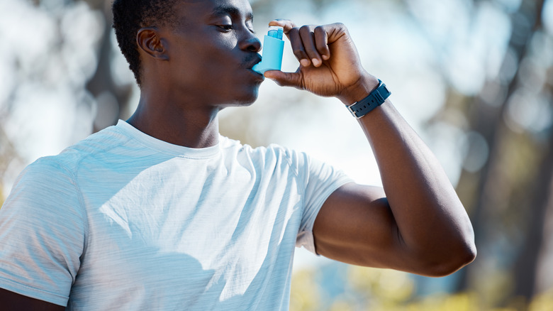 man using inhaler outdoors