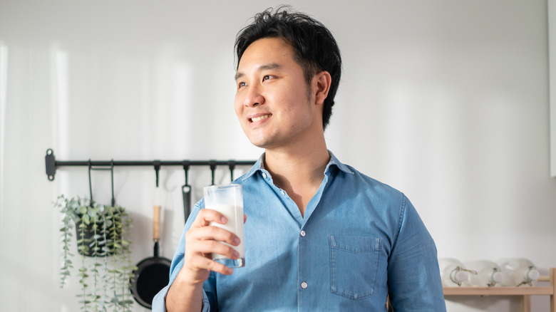 man smiling, holding glass of milk