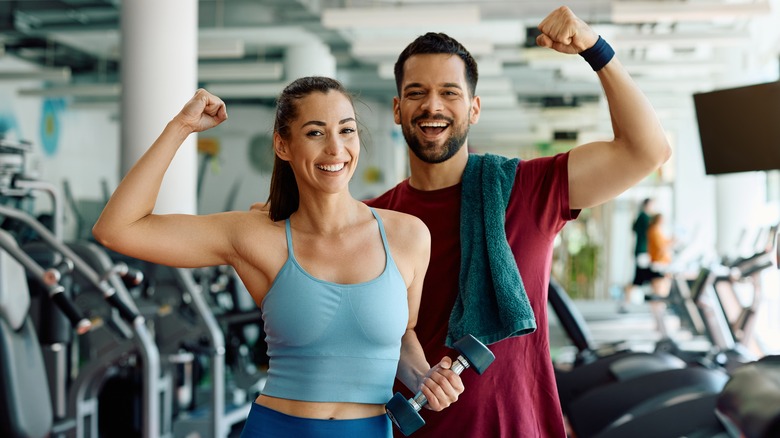 happy couple at the gym holding dumbbells