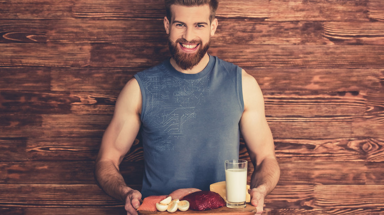 muscular man holding a tray full of protein sources