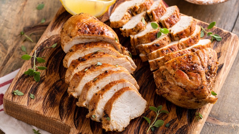 roasted chicken breast sliced on a wooden cutting board