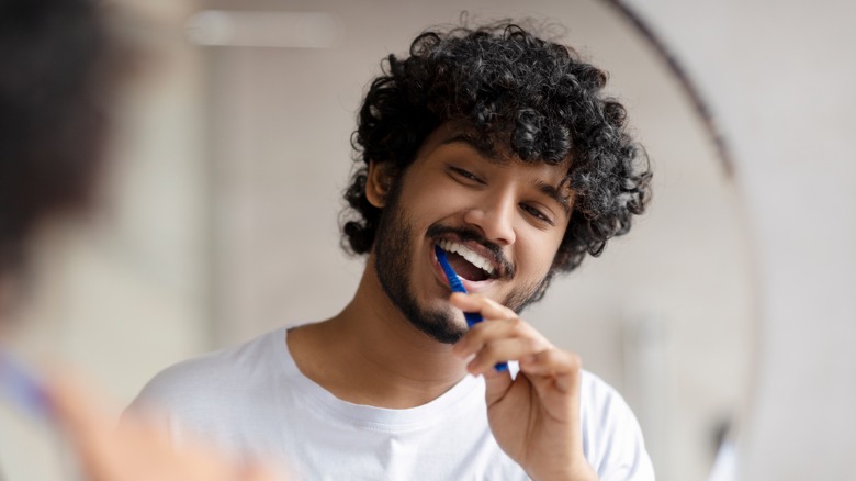 young man brushing teeth smiling