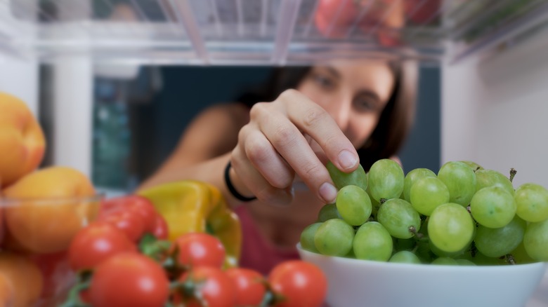 Woman touching grapes in fridge