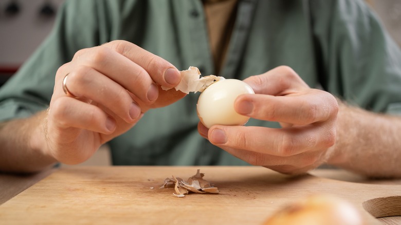 man's hands peeling a hard-boiled egg