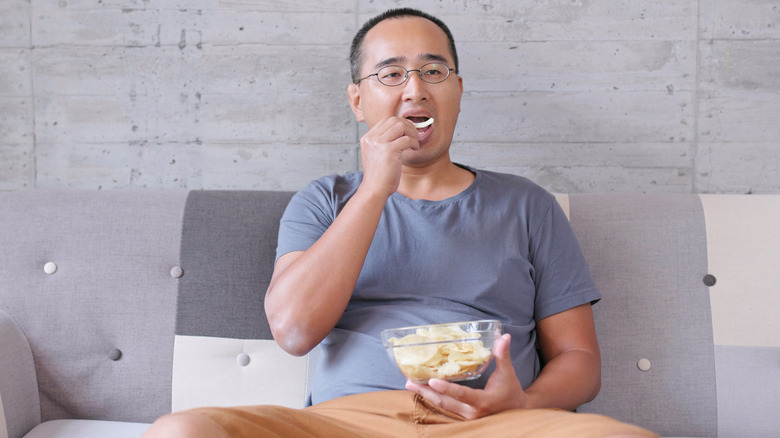 Man eating bowl of potato chips