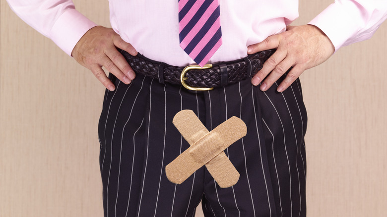 man with two bandages making a cross over pelvic area