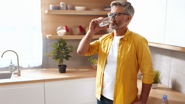 man drinking water in kitchen