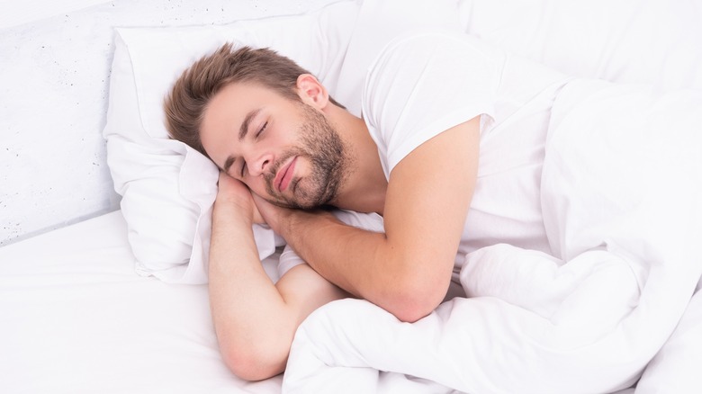 man sleeping blissfully in white bed