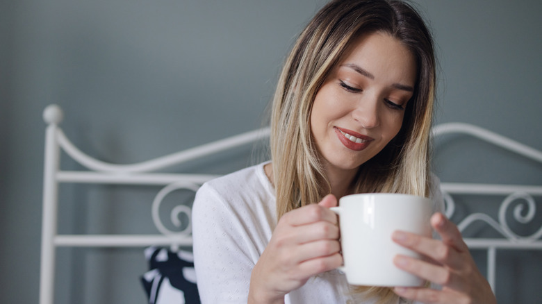 woman sitting in bed drinking from a mug