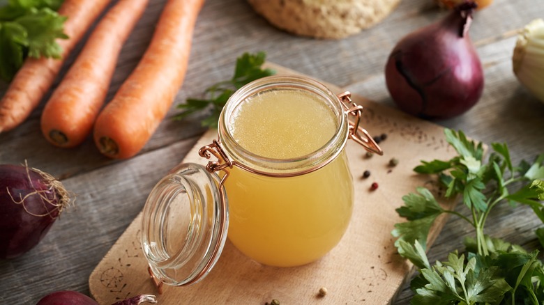 small jar of bone broth surrounded by vegetables