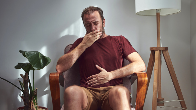 man with one hand on stomach and another over mouth