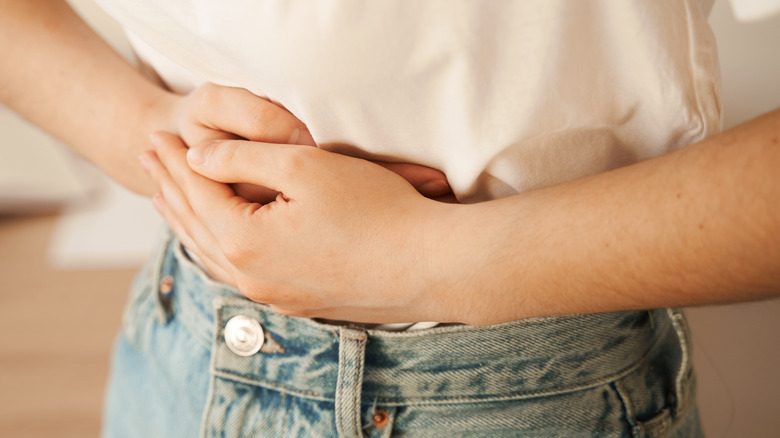 Hands over white shirt covering abdomen