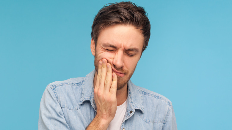 Man holding sore mouth