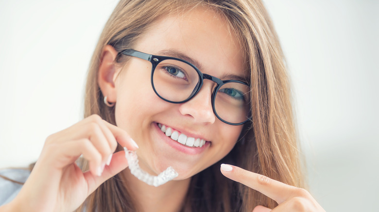 girl smiling and pointing to retainer