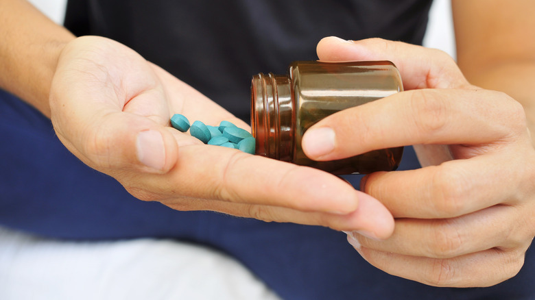 hand taking several blue pills