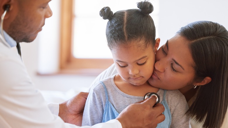 A little girl with her mother being examined by a doctor