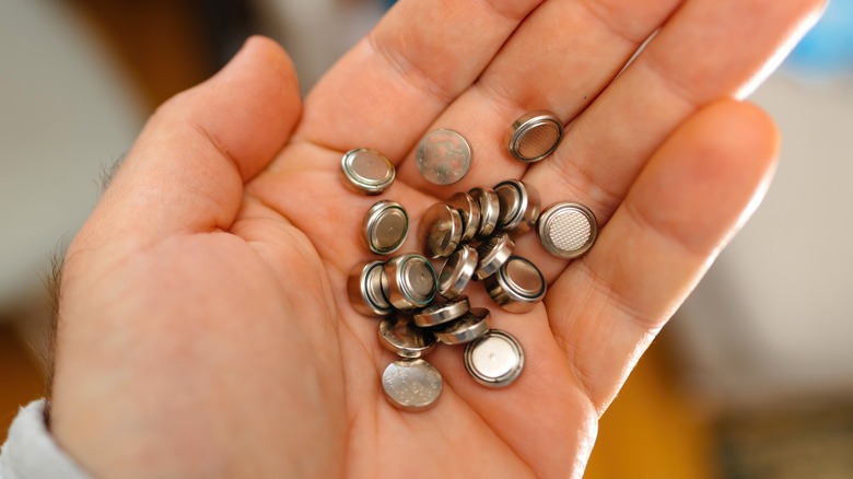 Button batteries on a man's palm