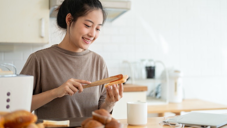 smiling young woman spreading preserves on bread