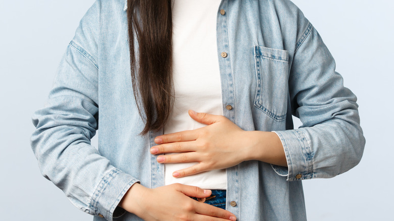 A woman puts her hands on her stomach