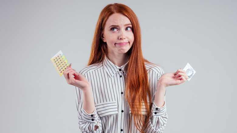 Woman holding condom and pills