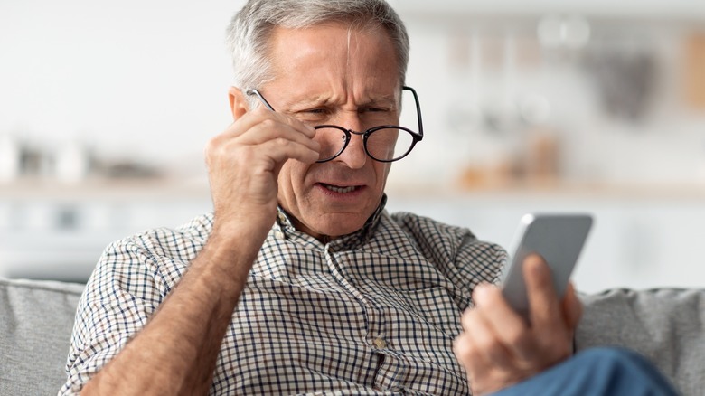 Old man squinting at phone