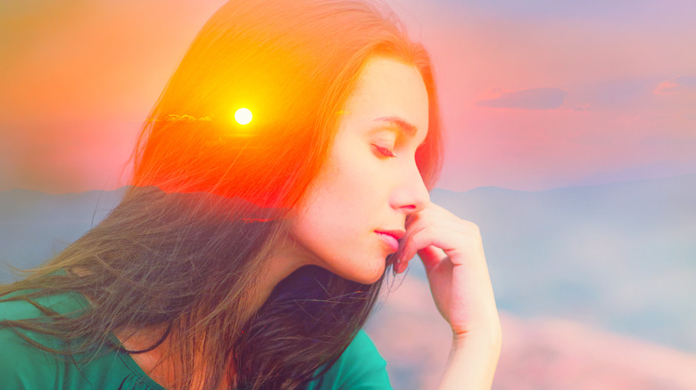 Translucent image of woman against sunset