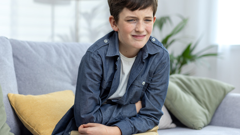 boy holding stomach and grimacing