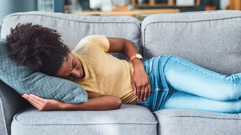 woman on couch holding stomach