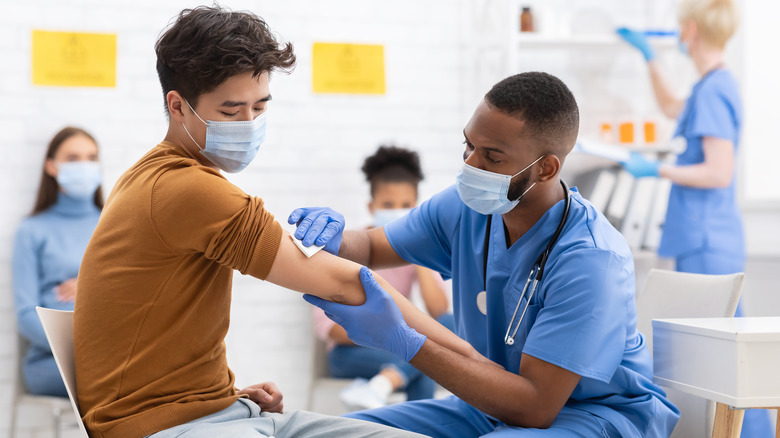 young male receiving  COVID-19 vaccine from a health care professional 