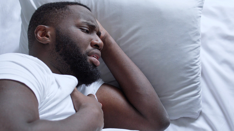 Man waking up scared clutching his chest