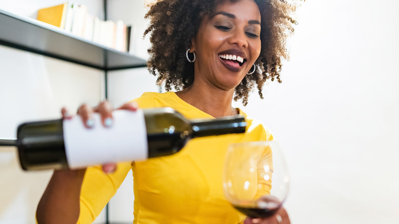 Happy woman pouring wine into glass