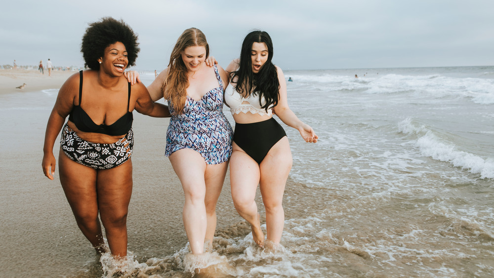 models of different sizes walking together on beach