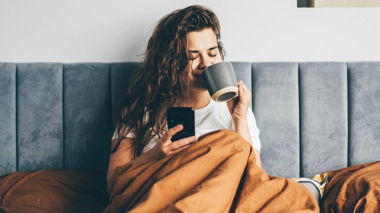 woman checking phone in bed