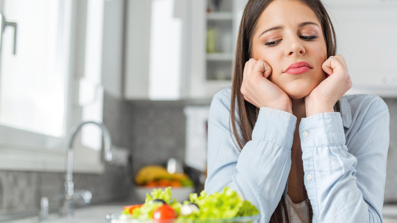 stressed woman looking at salad in bowl