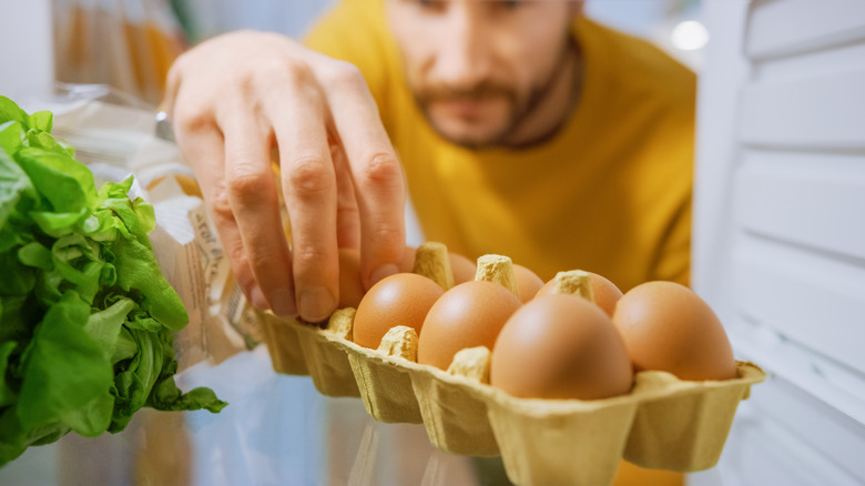 man getting eggs from refrigerator