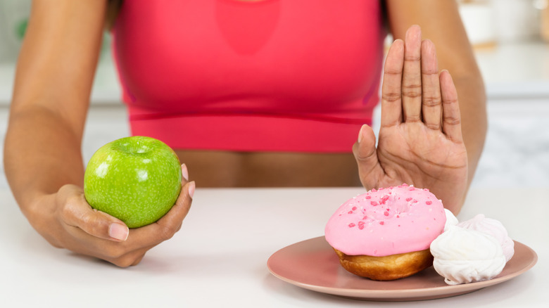 Close up of girl giving up eating cake, choosing green apple