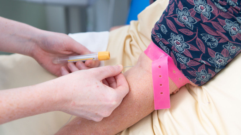 A nurse prepares to take blood from a patient's arm