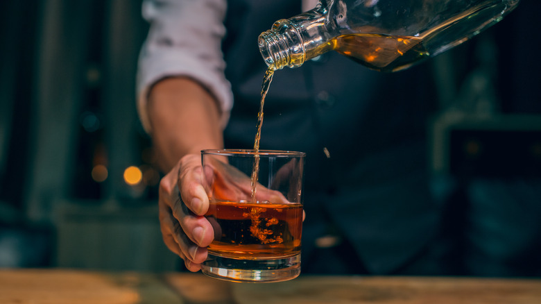 Close up of man pouring rum into a glass