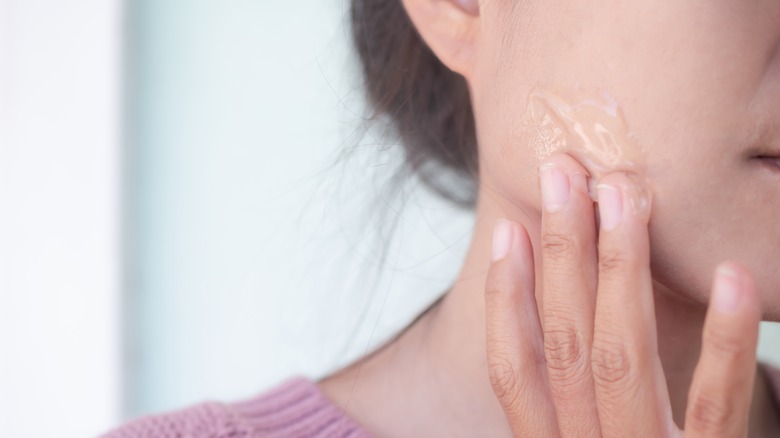 Woman rubbing aloe vera on face