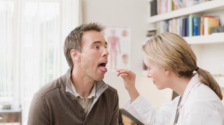 doctor examining patient tongue 