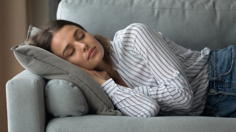 Woman napping during the day on a gray couch