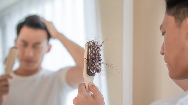 man losing hair looking at brush
